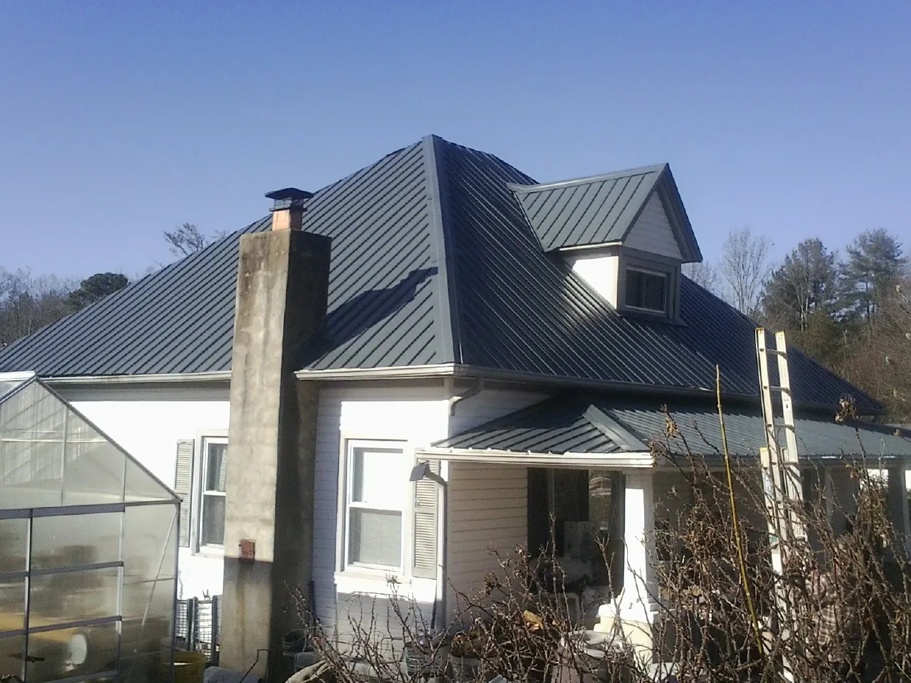 Dark blue standing seam metal roof on a white farmhouse with dormer — Slate & Tile Roof Repair by Roofing Brothers in Mount Hood Parkdale
