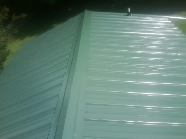 New green metal panels meeting at the ridge of a roof — Flat Roof Repair work by our crew in Mount Hood Parkdale