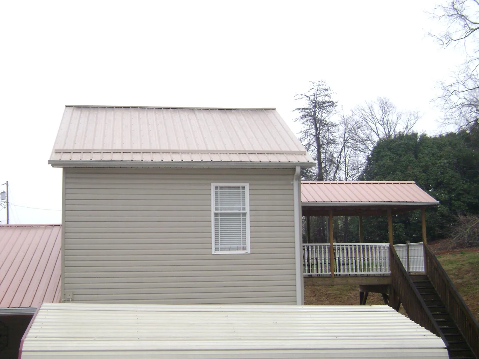 Tan metal roofs on a two story addition and attached porch, from a Roof Replacement job in Mount Hood Parkdale