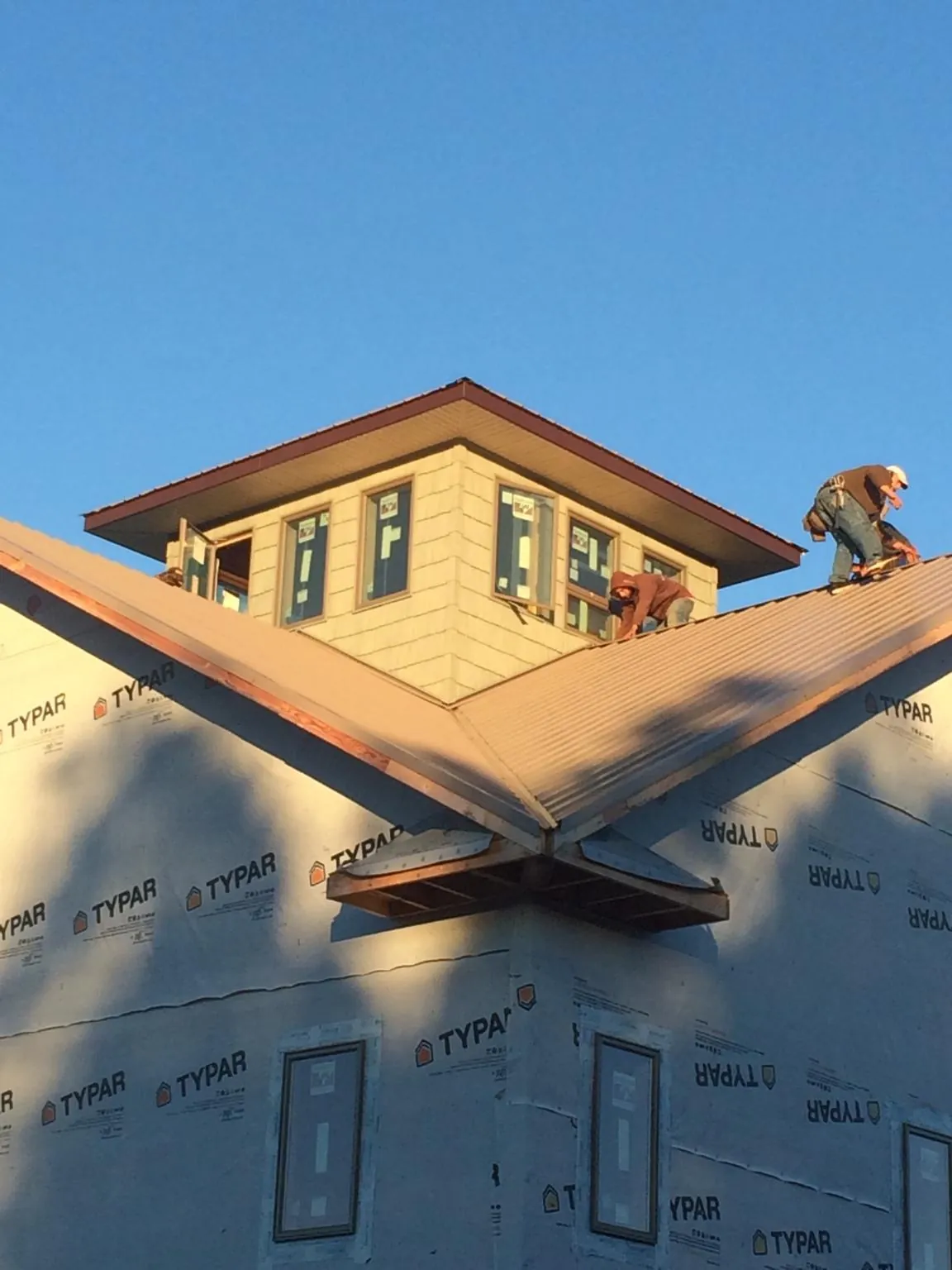 Roofers working around a rooftop cupola on a new metal roof at sunset — Roof Waterproofing in Mount Hood Parkdale by Roofing Brothers